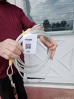 Person holding coiled metal cable dog lead with yellow plastic parts and metal clip, showing length and condition.