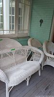 Porch view showing one set’s loveseat and chairs in white wicker.