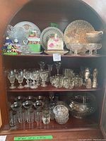 Shelf with assorted glass plates, punch bowl, glasses, dessert bowls, and other serving pieces.