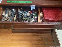 Drawer with assorted metal cutlery and kitchen utensils, including forks, spoons, knives, and some kitchen tools.