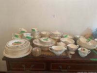 Full view of the Georgian china set showing multiple tea cups, saucers, plates, gravy boat, milk and sugar set, and creamer arranged on table.