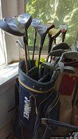 Blue Kenmore golf bag filled with assorted golf clubs including 3 wood, 5 wood, and irons.