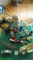Overview of mid-century decor items on green table including vases, figurines, and clock