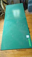 Top view of green metal folding table showing surface condition and overall rectangular shape.