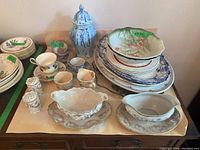 Overall view of assorted vintage ceramic serveware, tea sets, and salt and pepper shakers on display surface.