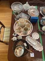 Overview of the vintage china tea set with silver and glass pieces on wooden table.