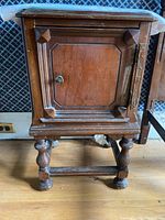 Front and side view of wood side table showing paneled cabinet door and turned legs.