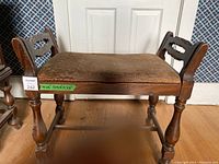 Front angle view of wooden bench showing armrests and upholstered seat.