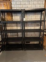 Front view of two black plastic shelving units side by side against a brick wall.