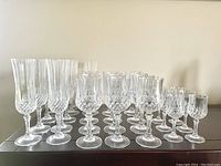 Front view of the full set of Cristal D’Arques crystal glasses arranged with champagne flutes, wine glasses, and cordial glasses.