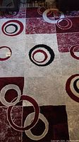 Full view of the geometric patterned area rug showing red, black, grey and white circles and square blocks.