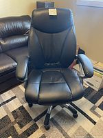 Front view of the black faux leather office chair showing padded seat, backrest and armrests.