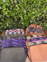 Four vintage boho tapestry bags arranged together, showcasing colorful geometric woven textile patterns and leather trims.