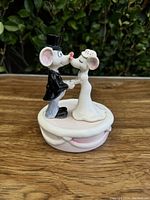 Front view of the ceramic wedding music box with two mouse figurines dressed as a bride and groom kissing.