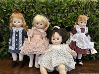 Four vintage Madame Alexander dolls shown outdoors, each dressed in distinct period and floral outfits with some new with tags