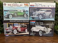 Four boxed vintage model car kits stacked and arranged to show front box art: 1931 Cadillac, 1932 Cadillac V-16, Mercedes 540K Cabriolet, Packard Phaeton Speedster