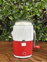Front view of vintage Rival Vogue Ice-o-Mat ice crusher showing red and white metal body, clear dome top, and some paint wear.