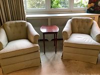 Two vintage tub armchairs and one small wooden side table arranged in front of window