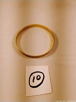 Top-down view of entire bangle placed on white surface with lot number card