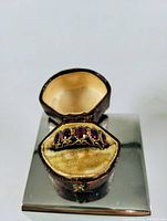 Ring displayed inside original leather-lined box on mirrored surface
