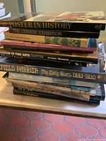 Stack of approximately twelve vintage art books on a table showing spines with various titles related to art and history.