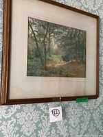 Frontal view of framed watercolour painting showing woodland landscape with clear water stains visible on matting.