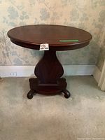 Full view of the Victorian oval parlour table showing the oval top and central harp-shaped base with four feet.