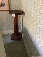 Full view of the vintage solid wood pedestal stand showing its height and slender column support.