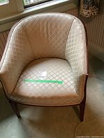 Front view of a vintage tub chair with silk upholstery featuring a diamond pattern and wooden legs.