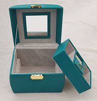Front view of open jewelry box showing mirror on lid, main velvet-lined compartment and removable trays for storage.