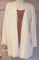 Front view of cream, open front, long sleeve cardigan on mannequin showing solid color and lightweight knit.