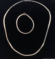 Herringbone necklace and bracelet displayed on black background, showing full length of both items.