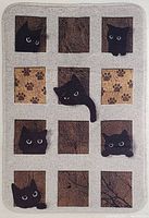 Top view of rectangular kitchen mat with alternating brown textured squares and black kitten faces on a light beige background.