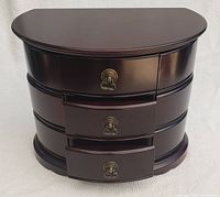 Front view of the polished wood jewelry box with three large pull-out drawers and brass handles.