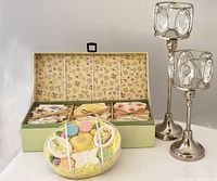 Photo showing two silver plated candle holders with attached oval crystal prisms, decorative boxed note cards with floral pattern inside box lid, and boxed decorative soaps in pastel colors arranged in oval dish.