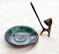 Photo of handmade pottery ring bowl and brass cat ring holder on light fabric background