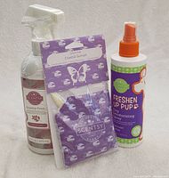 Three Scentsy products: Fresh Fabric Spray spray bottle with trigger top, Coastal Sunset Scent Pak in a sealed purple pouch, Freshen Up Pup Dog Deodorizing Spray with orange pump spray.