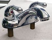 Chrome bathroom sink faucet with two curved lever handles and central spout with threaded fittings.