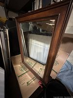Full view of the rectangular bathroom mirror showing the dark wooden frame and bevelled glass edge.