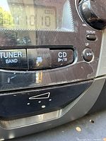 Close-up of control panel with tuner band, CD play/pause button, repeat and up buttons visible.