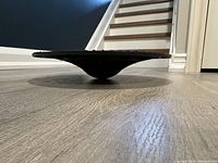 Side view of the black Nike balance disc slightly elevated from floor showing shape and profile