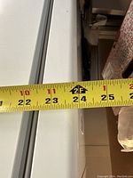 Tape measure showing freezer length approximately 24 inches.