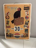 Front photo of the Italian manual perpetual calendar showing date 30 March, with vintage travel stickers and bird illustration.