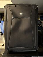 Front view of large black Samsonite soft-sided luggage with visible zippered front pocket and logo.