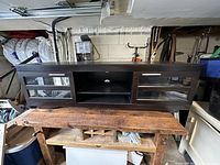 Front view of dark rectangular media unit with two glass sliding doors and metal handles. The unit rests on a wooden surface.