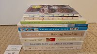 Stack of seven Anna Olsen baking cookbooks showing spines and partial front covers.