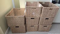 Eight deep wicker baskets stacked and grouped in two sizes, showing natural color, woven texture, and cutout handles.