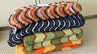 Stack of four crochet Afghan throw blankets showing colors and pattern