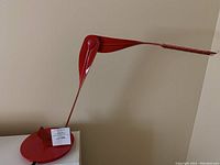 Front-right view of red lamp folded mid-arm above round base