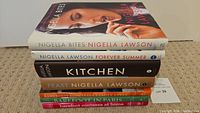 Stack of seven hardcover cookbooks by Nigella Lawson and Ina Garten, with visible titles and authors on spines and covers.
